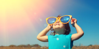 Kind met grote zonnebril kijkt naar de zon