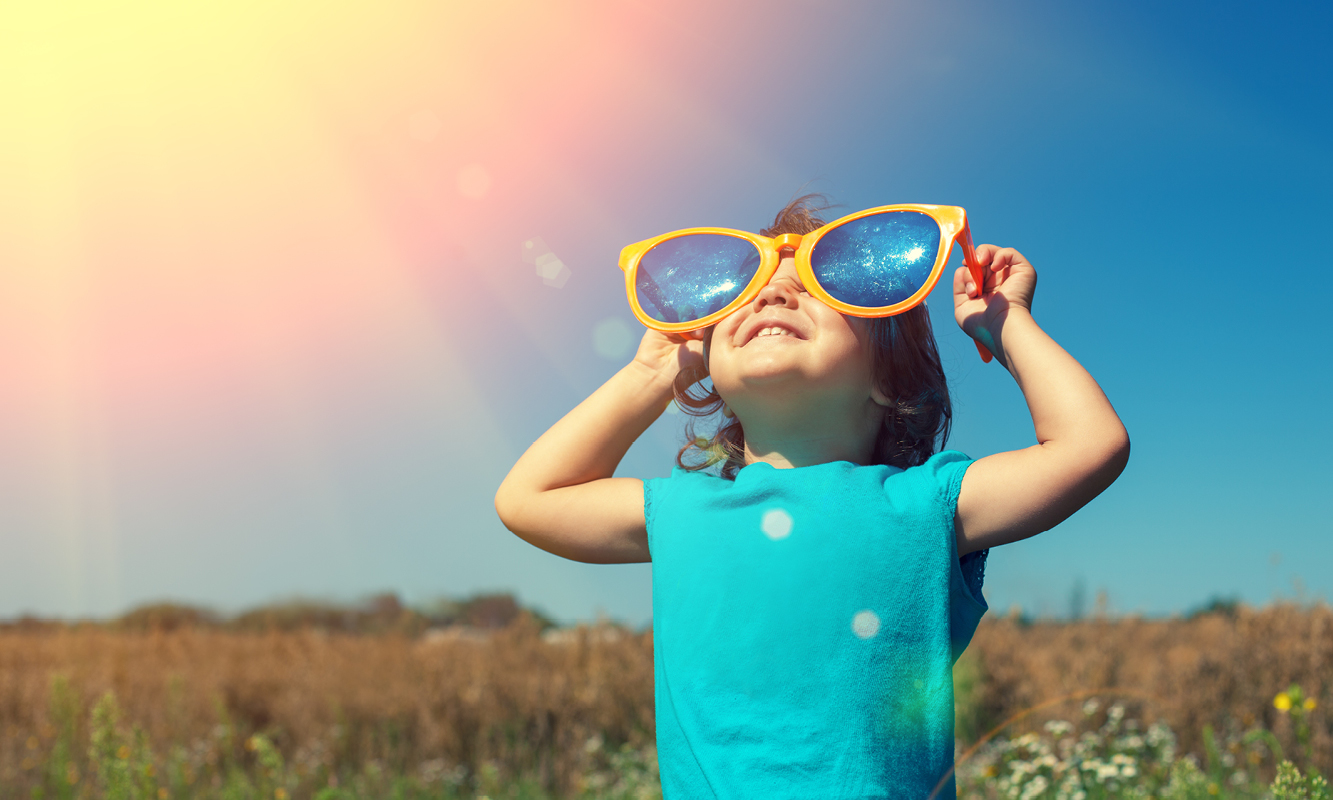 Kind met grote zonnebril kijkt naar de zon